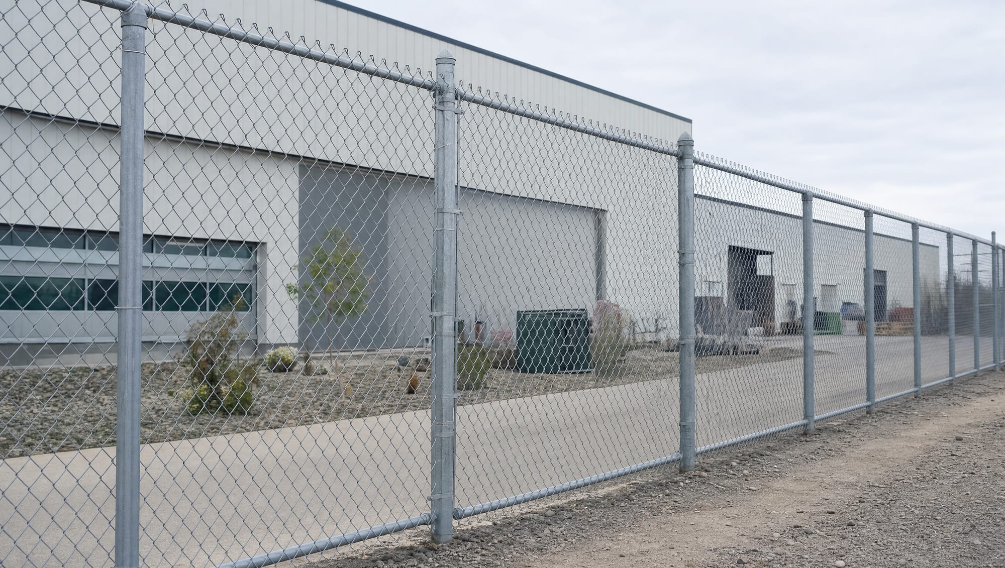 A tall galvanized chain link fence securing the perimeter of an industrial building